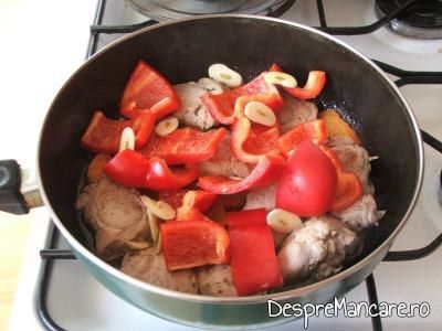 Adaugare de felii de ardei gras si feliute de usturoi pentru muschiulet de porc cu legume, la tigaie.