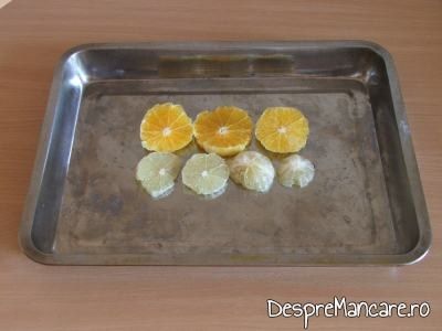 Felii de lamai si de portocale asezate pe fundul tavii pentru crap cu legume, lamai si portocale la cuptor.