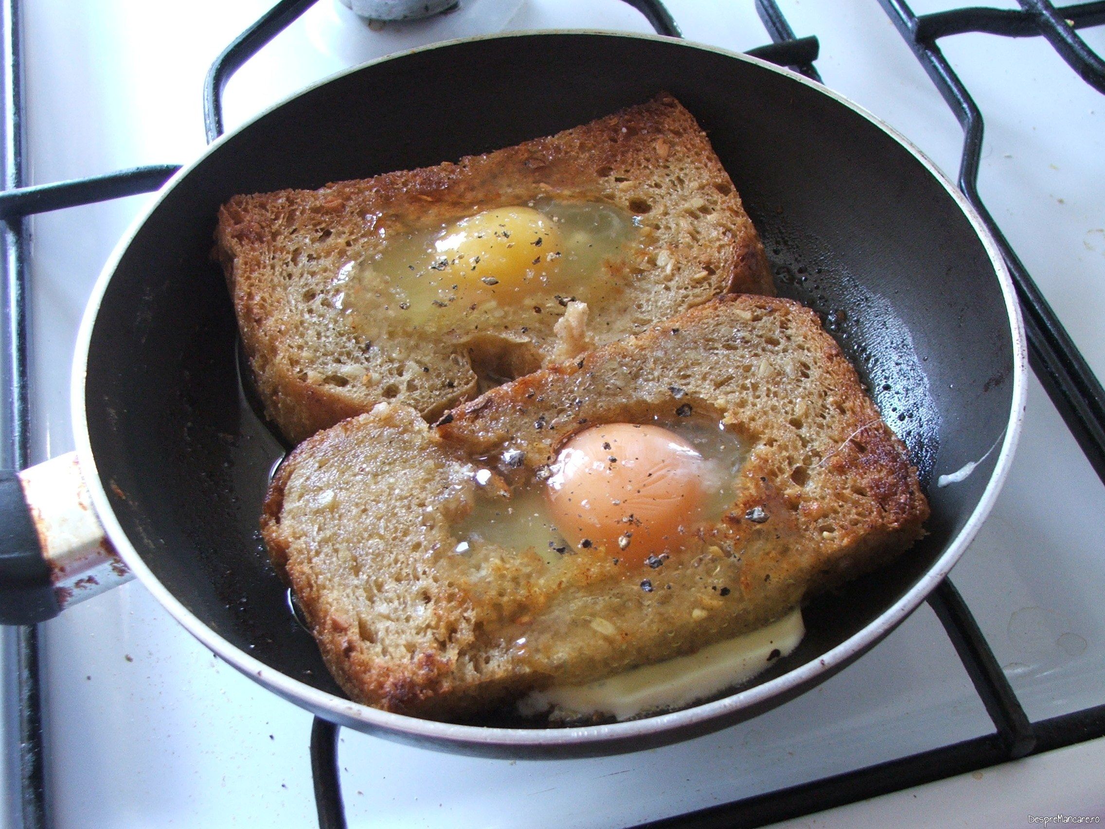 Oua de gaina scoase din coaja, puse in gaura de la feliile de paine pentru ochiuri cu cascaval afumat si paine prajita.