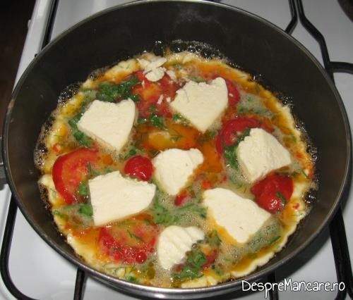 Felii subtiri de telemea de oaie/ capra si/ sau cascaval afumat adaugate in ouale batute pe jumatate coapte pentru omleta cu rosii.