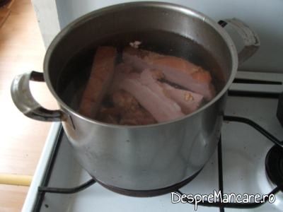 Scarita de porc, afumata, taiata in bucati pusa la fiert in apa rece pentru ciorba din scarita de porc afumata.