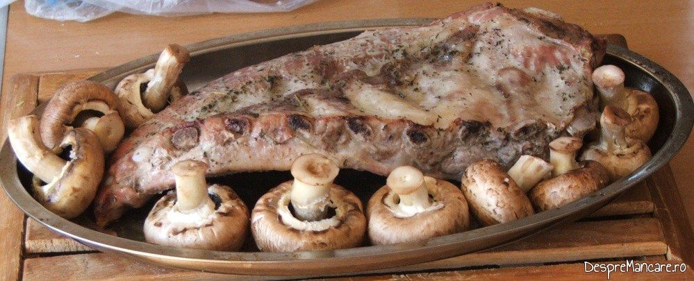 Coaste de porc si ciuperci proaspete asezate in tava de copt pentru coaste de porc la cuptor cu piure de legume.