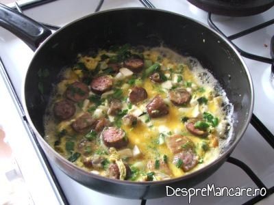 Adaugare oua batute pentru omleta cu porcarele, ceapa si usturoi verde.