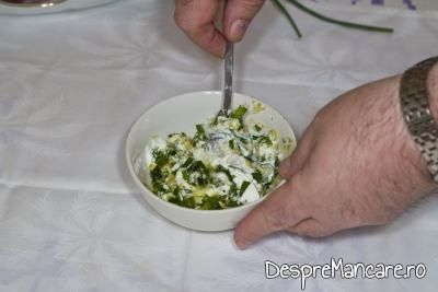 Amestecarea mujdeiului din usturoi uscat, usturoi verde si iaurt, cu furculita.