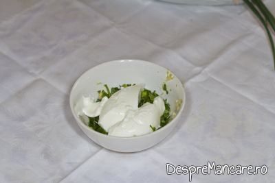 Adaugare iaurt gras in amestecul de usturoi, ulei de masline si verdeata pentru mujdei din usturoi uscat, usturoi verde si iaurt.
