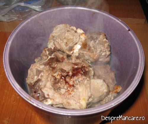 Carne de berbec, rumenita, asezata pe legume in vasul de ceramica pentru varza murata fiarta cu carne de berbec.