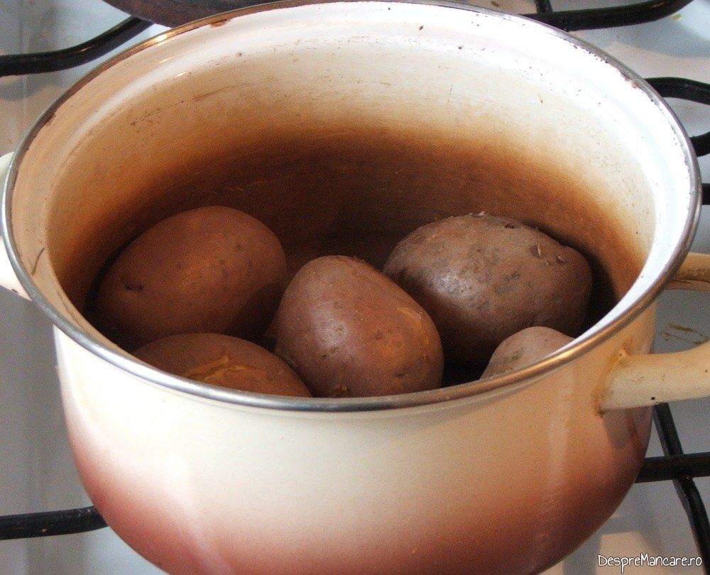 Cartofi fierti pe jumatate pentru spata si carnati proaspeti de porc, la cuptor.