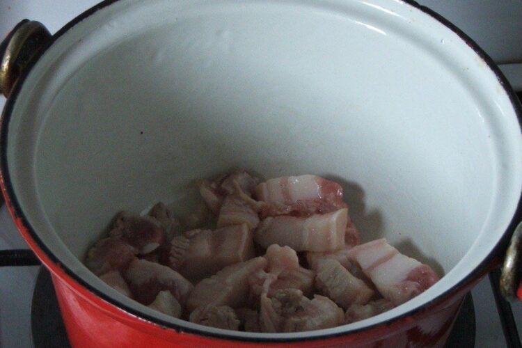 Prajire bucati din piept de porc in tuciul in care se va pregati reteta.