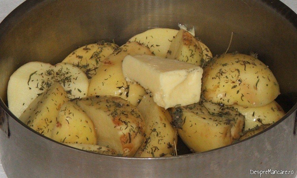 Cartofi noi taiati in 2/4 asezonati cu sare grunjoasa, ulei de masline, cimbru uscat pregatiti pentru a fi inabusiti.